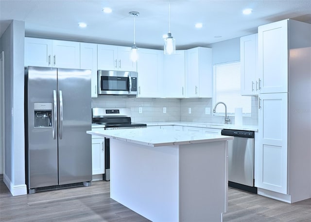 kitchen featuring a kitchen island, a sink, appliances with stainless steel finishes, white cabinetry, and light wood-type flooring