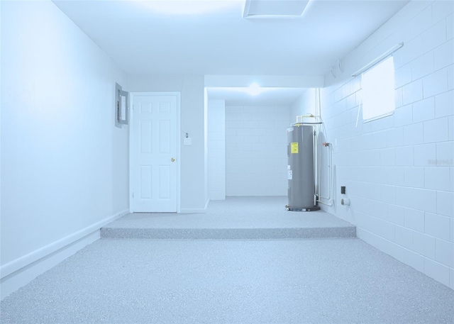 garage with electric water heater, concrete block wall, and baseboards