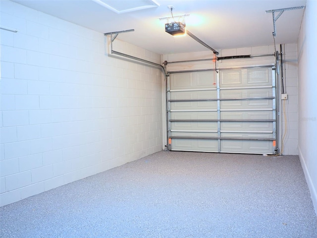 garage featuring concrete block wall and a garage door opener