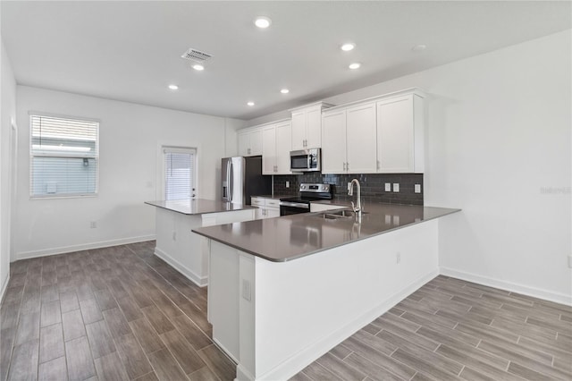 kitchen with visible vents, a sink, tasteful backsplash, a center island, and appliances with stainless steel finishes