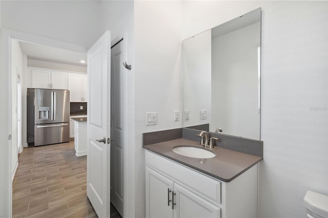 half bath with wood finish floors, decorative backsplash, toilet, and vanity