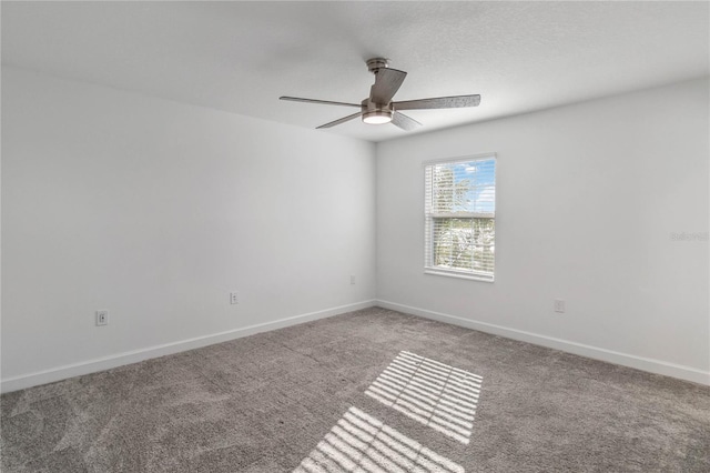 carpeted spare room featuring baseboards and a ceiling fan