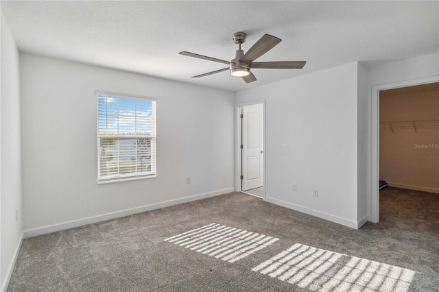 unfurnished bedroom featuring a walk in closet, ceiling fan, baseboards, carpet flooring, and a closet