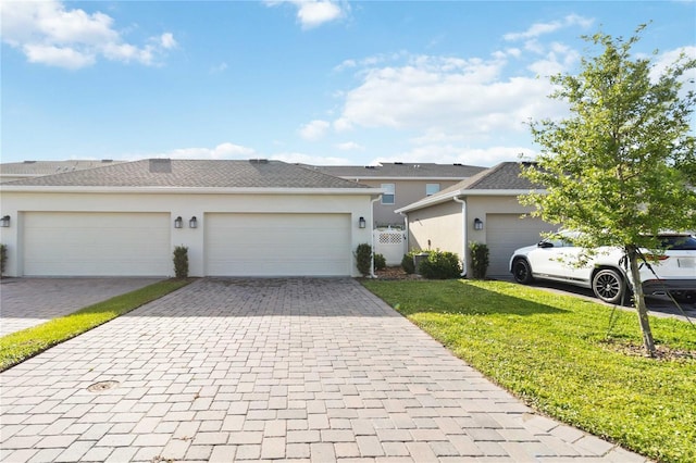 single story home featuring a front lawn, decorative driveway, a garage, and stucco siding