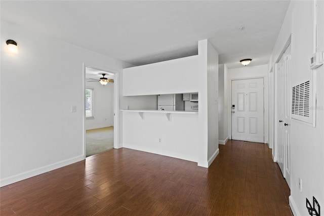 unfurnished living room with wood finished floors, baseboards, and ceiling fan