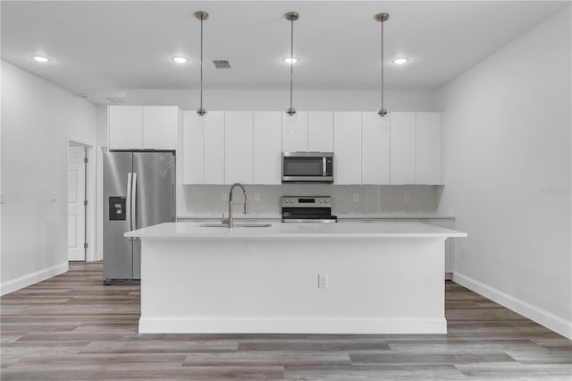 kitchen with visible vents, white cabinets, an island with sink, appliances with stainless steel finishes, and a sink