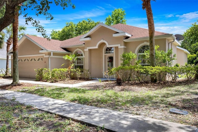 view of front of property with an attached garage, a shingled roof, and stucco siding