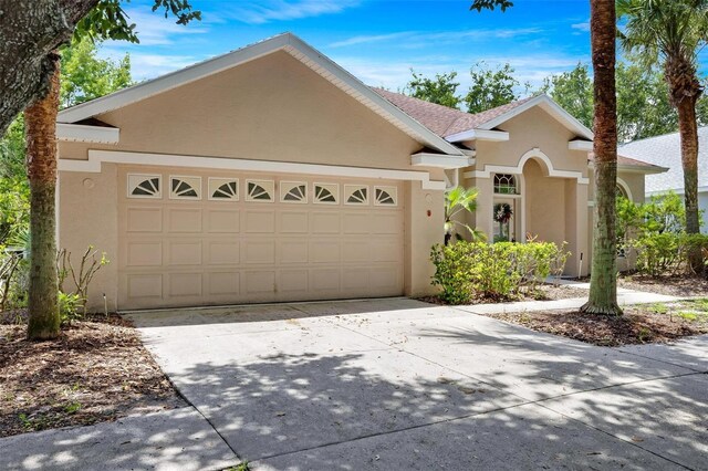 view of front facade with an attached garage, a shingled roof, concrete driveway, and stucco siding