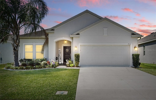 ranch-style home with stucco siding, a lawn, a garage, and driveway