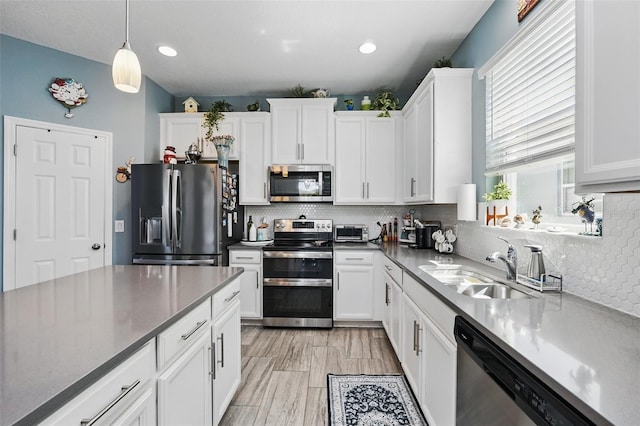 kitchen with backsplash, white cabinets, appliances with stainless steel finishes, and a sink