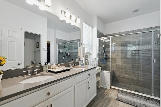 bathroom featuring double vanity, a stall shower, and a sink