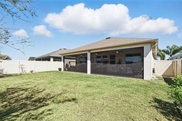 rear view of property with ceiling fan, a sunroom, stucco siding, a fenced backyard, and a yard