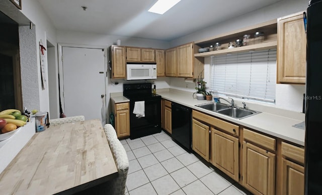 kitchen featuring light countertops, a sink, black appliances, and light tile patterned floors