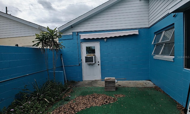 doorway to property featuring fence, concrete block siding, and cooling unit