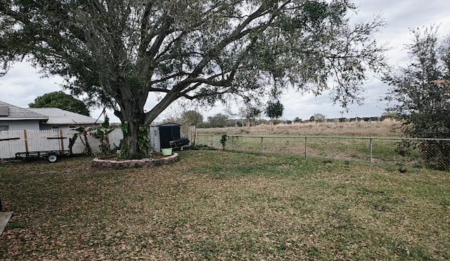 view of yard with an outbuilding, a fenced backyard, and a shed