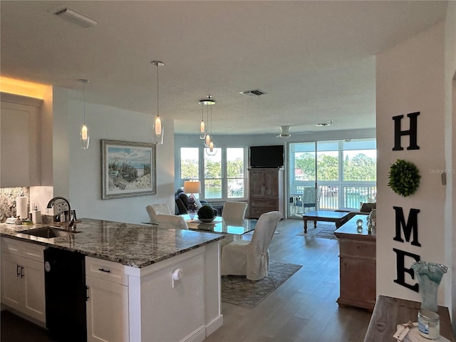 kitchen with visible vents, a healthy amount of sunlight, open floor plan, dishwasher, and a sink