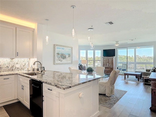 kitchen with visible vents, open floor plan, dishwasher, a peninsula, and a sink