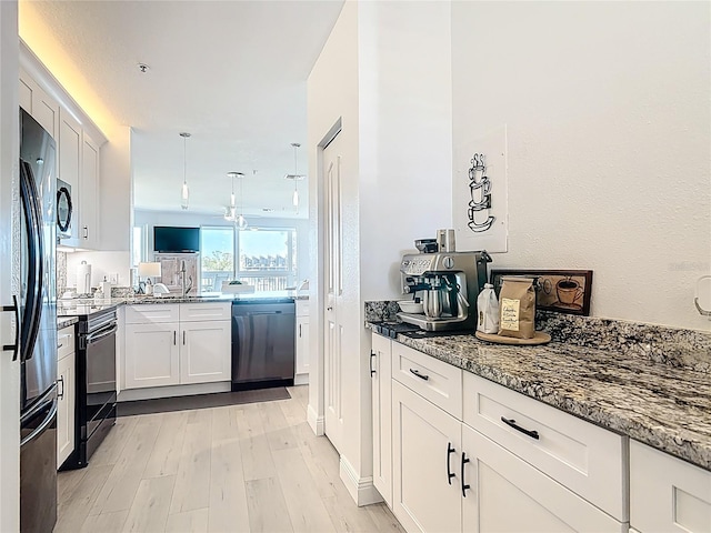 kitchen featuring dark stone counters, light wood-style floors, black appliances, and white cabinets