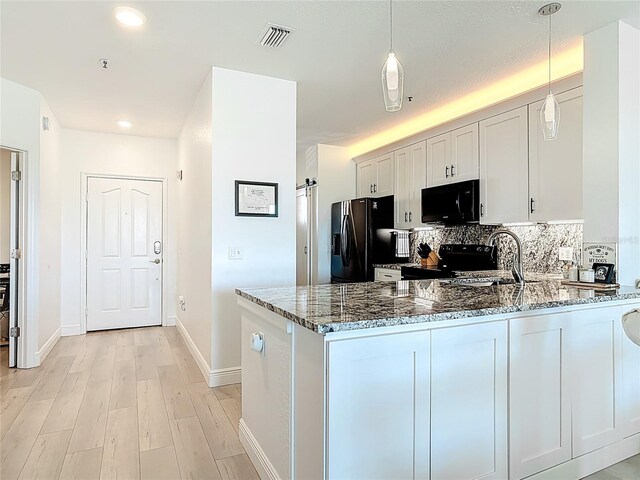 kitchen featuring tasteful backsplash, visible vents, stone countertops, black appliances, and a sink