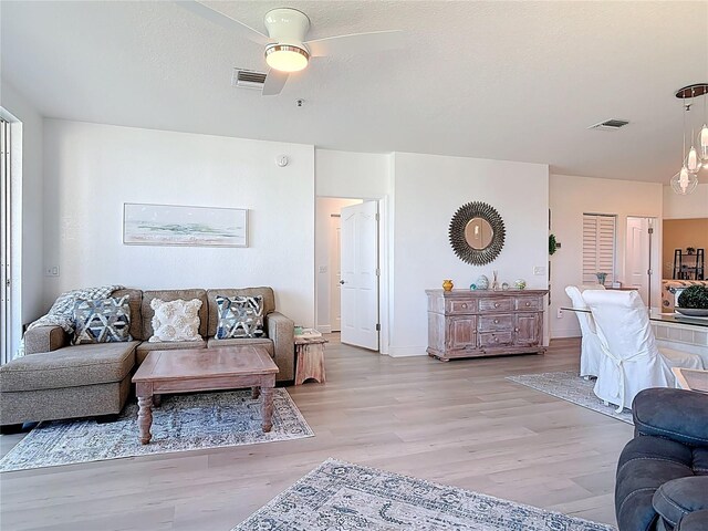 living room with visible vents, a textured ceiling, and light wood-type flooring