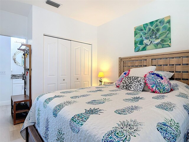 bedroom with wood finished floors, visible vents, and a closet