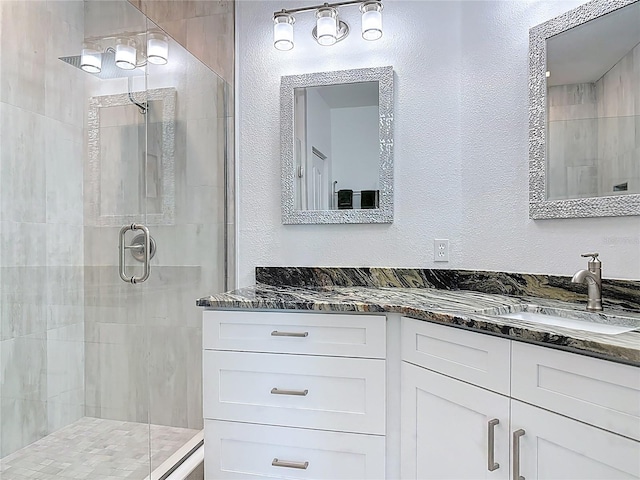 bathroom featuring a stall shower, vanity, and a textured wall