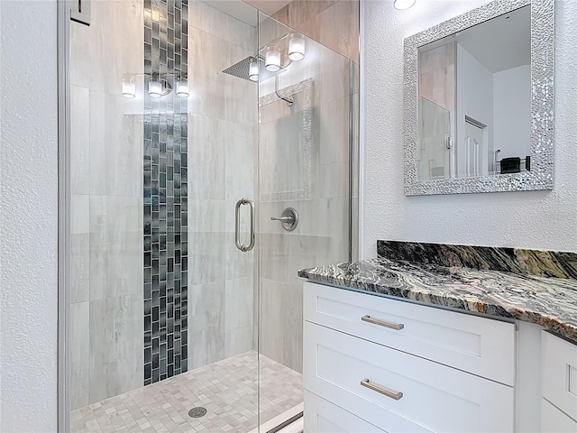 full bath featuring a stall shower, vanity, and a textured wall