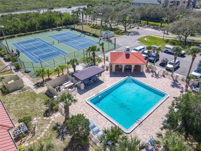 community pool featuring outdoor dry bar, a tennis court, fence, a gazebo, and a patio area