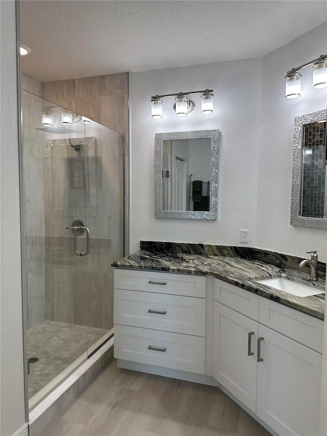 434 Bouchelle Dr Unit 202, New Smyrna Beach, FL 32169 - bathroom featuring a shower stall, wood finished floors, a textured ceiling, vanity, and a textured wall