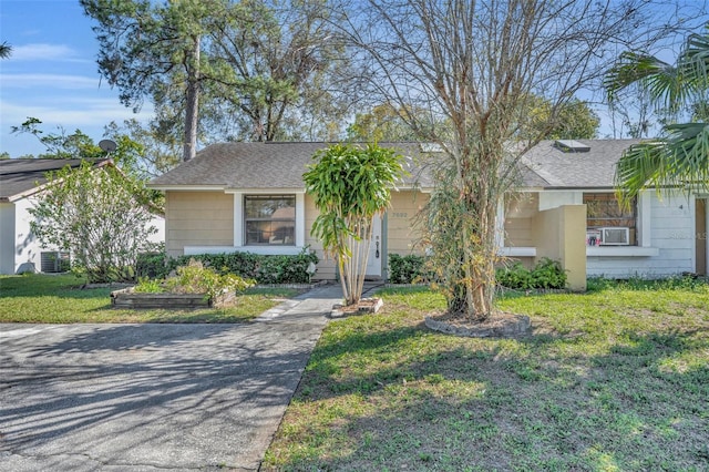 view of front of home featuring central air condition unit, roof with shingles, and a front yard