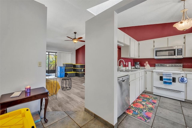 kitchen with light tile patterned floors, stainless steel appliances, light countertops, white cabinetry, and a sink