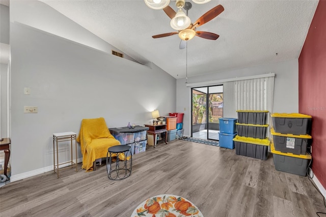 sitting room with vaulted ceiling, a textured ceiling, baseboards, and wood finished floors