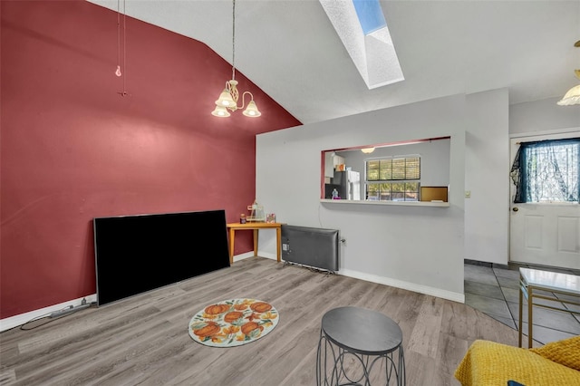 living area with lofted ceiling with skylight, a chandelier, baseboards, and wood finished floors