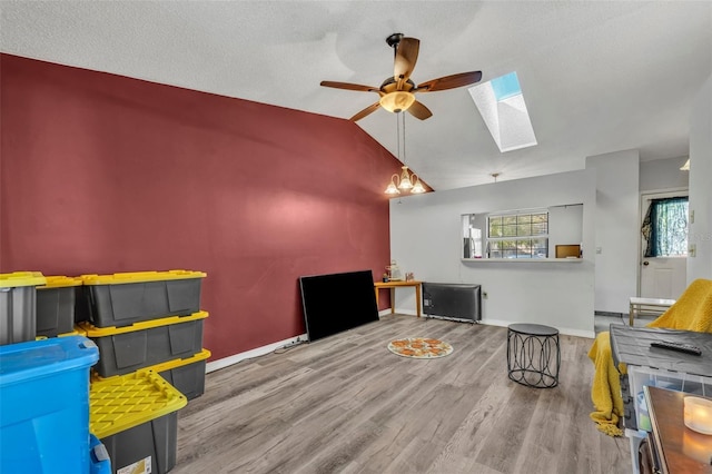 game room with lofted ceiling with skylight, plenty of natural light, wood finished floors, and baseboards