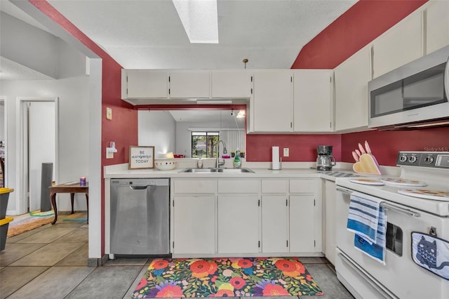 kitchen with light tile patterned floors, stainless steel appliances, a skylight, a sink, and light countertops