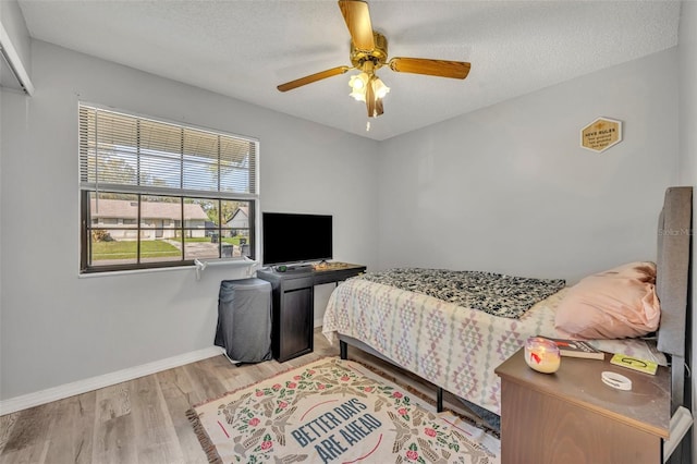 bedroom featuring a textured ceiling, ceiling fan, wood finished floors, and baseboards