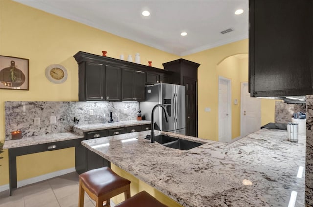 kitchen featuring visible vents, stainless steel fridge with ice dispenser, light stone counters, arched walkways, and a sink