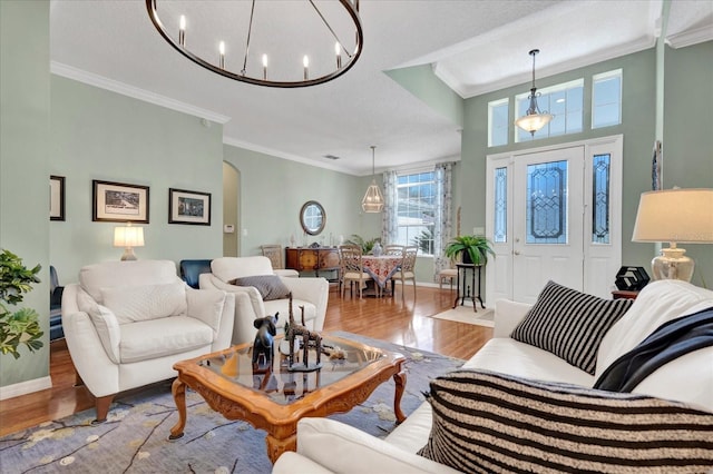 living room with crown molding, baseboards, an inviting chandelier, wood finished floors, and arched walkways