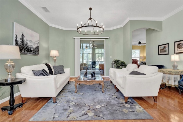 living area featuring visible vents, ornamental molding, wood finished floors, arched walkways, and baseboards