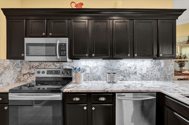 kitchen with tile patterned floors, light stone counters, tasteful backsplash, appliances with stainless steel finishes, and crown molding