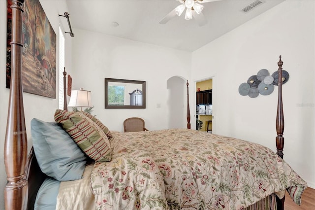 bedroom featuring ceiling fan, visible vents, arched walkways, and wood finished floors