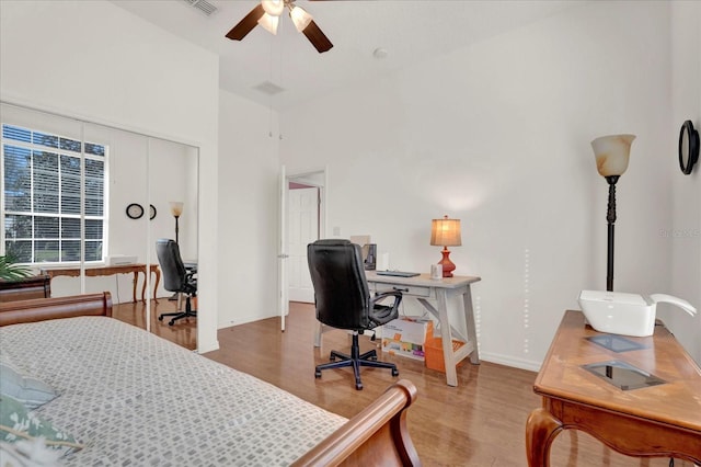 bedroom featuring light wood-style flooring, high vaulted ceiling, baseboards, and a ceiling fan