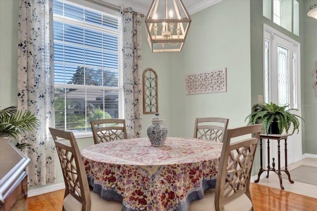 dining area with baseboards, crown molding, an inviting chandelier, and wood finished floors