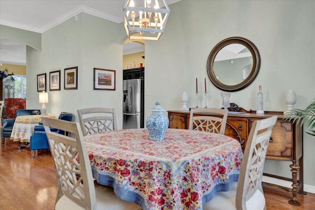 dining room featuring baseboards, a chandelier, ornamental molding, wood finished floors, and arched walkways