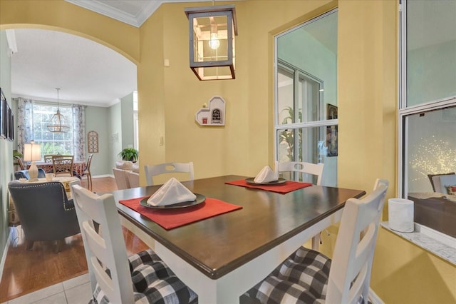 dining room with tile patterned floors, arched walkways, and ornamental molding