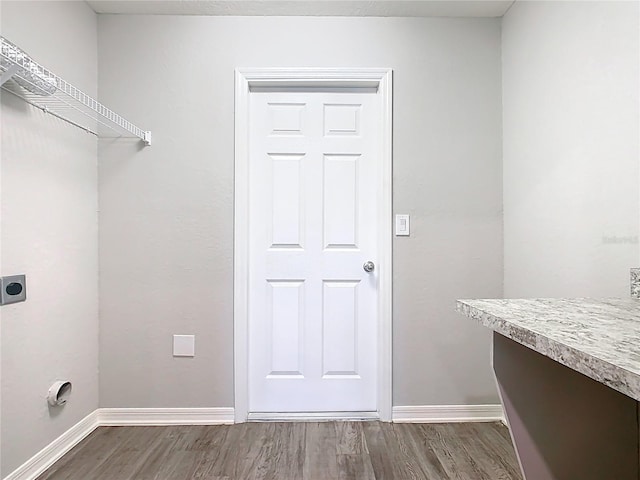 washroom featuring electric dryer hookup, baseboards, wood finished floors, and laundry area