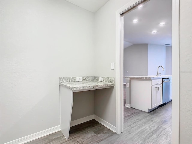 clothes washing area with light wood-style floors, baseboards, and a sink