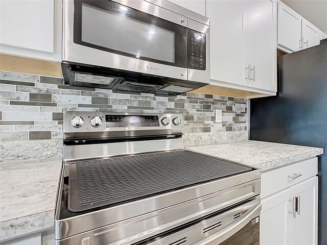 kitchen featuring tasteful backsplash, white cabinetry, stainless steel appliances, and light countertops