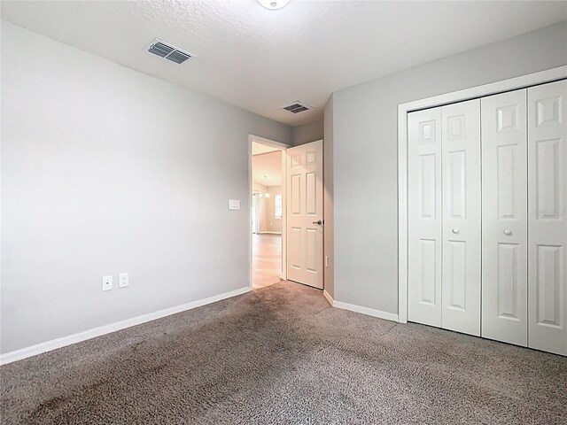 unfurnished bedroom featuring a closet, visible vents, baseboards, and carpet