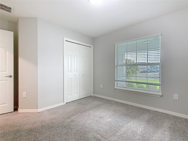 unfurnished bedroom featuring a closet, visible vents, baseboards, and carpet floors